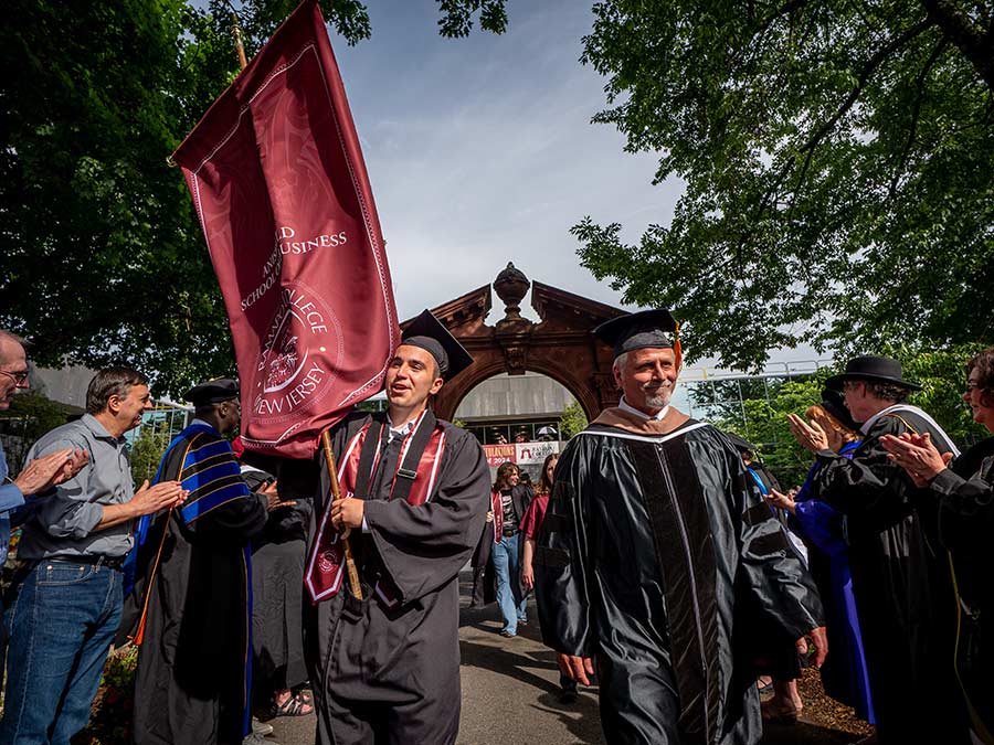 Ramapo College Arching ceremony with a dean and student walking through the arch in regalia