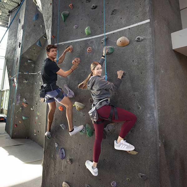 Two Ramapo College students indoor rock climbing.