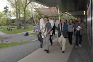 Our procession from Friends Hall to the Gross Center. The Torah is accompanied by two additional scrolls and is under a Jewish wedding canopy.