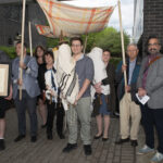 Students and faculty with Torahs under a canopy held up by four poles (a Jewish wedding canopy)