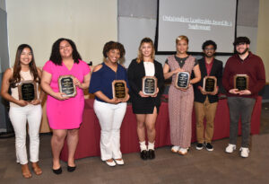 This picture has seven student leader holding awards at the reception. 