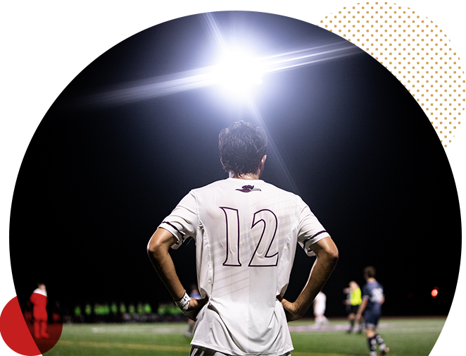 RCNJ soccer player with a bright light shining on him at night