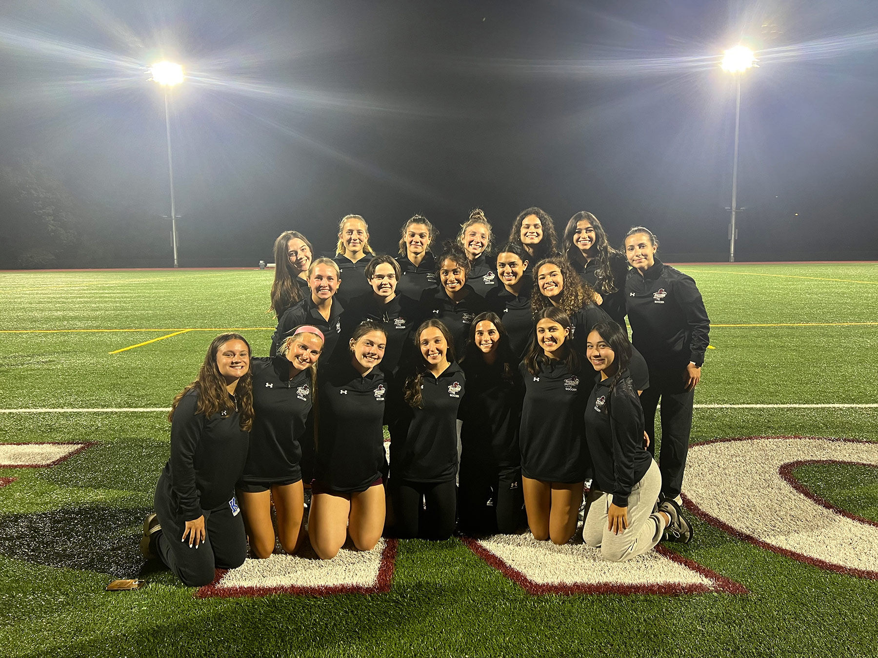 RCNJ Women's athletic team on a well lit turf