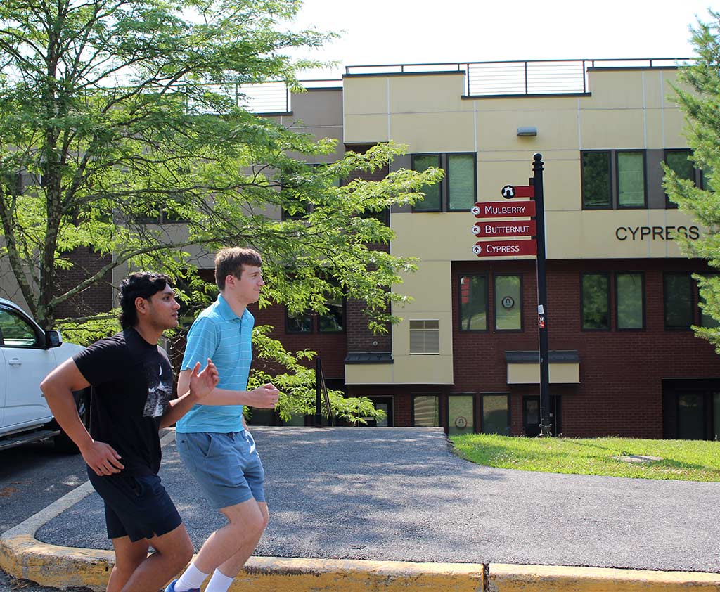 Two joggers running pass the Cypress College Park Apartments at Ramapo College