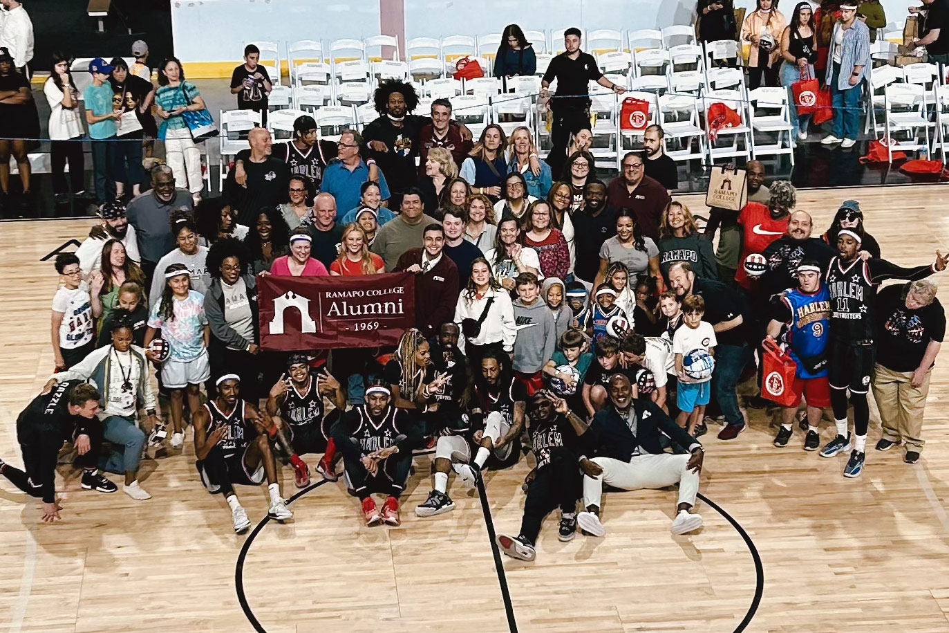 Group of alumni with the Harlem Globetrotters on a basketball court