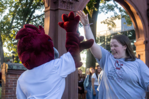 A student gives Rocky the Roadrunner a high-five at the Arching ceremony.