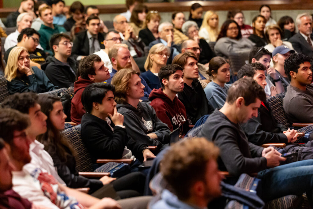 Students sitting in the theater looking at the stage to listen to Jonathan Gruber speak.