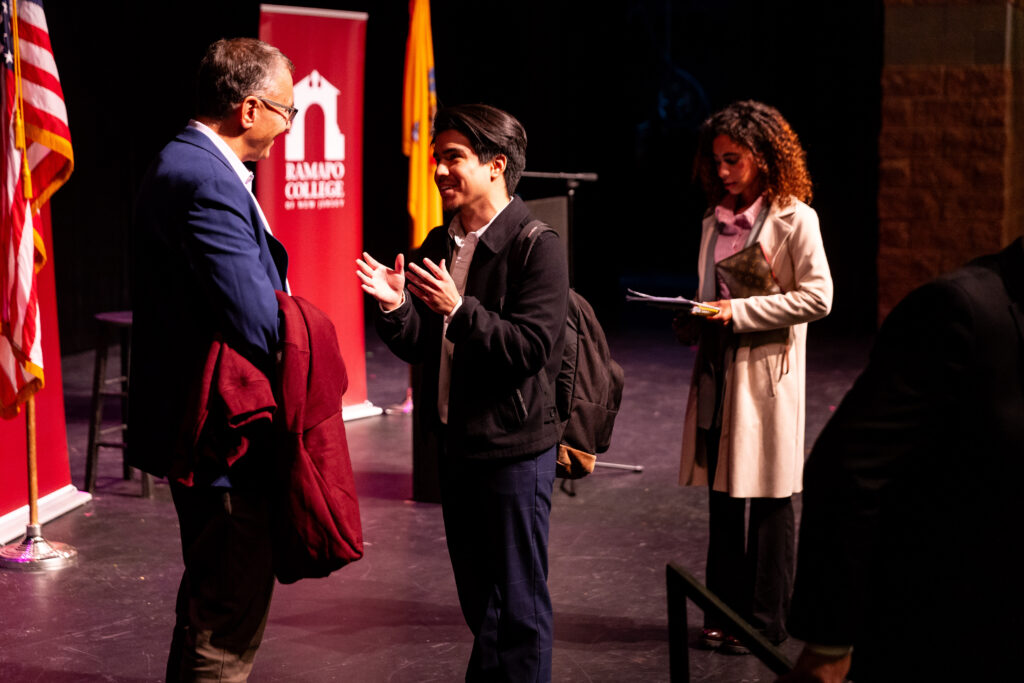 Two students stand on stage to speak with Gruber after his presentation.