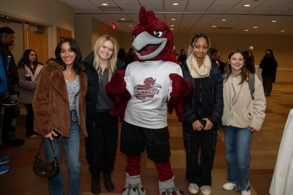 Four students stand around Rocky the Roadrunner inside the Student Center