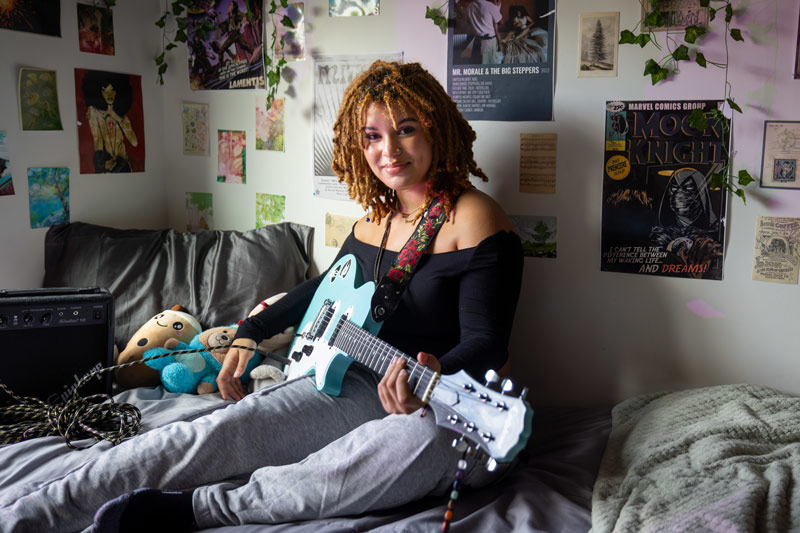 Student sitting in her dorm room playing a guitar at Ramapo College